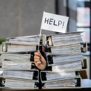A hand holding up a help flag behind a pile of files.