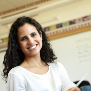 A young female teacher smiling and holding a pen
